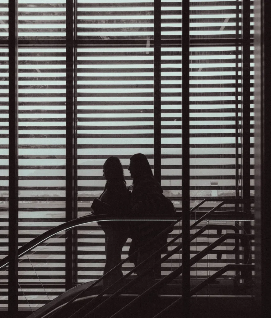 Two women heading to the escalators in an airport.