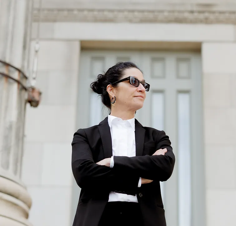 Lina Stillman confidently standing with arms crossed outside a New York courthouse